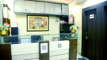 A reception desk with a glass partition, a framed Buddha statue, and a sign indicating a washroom.
