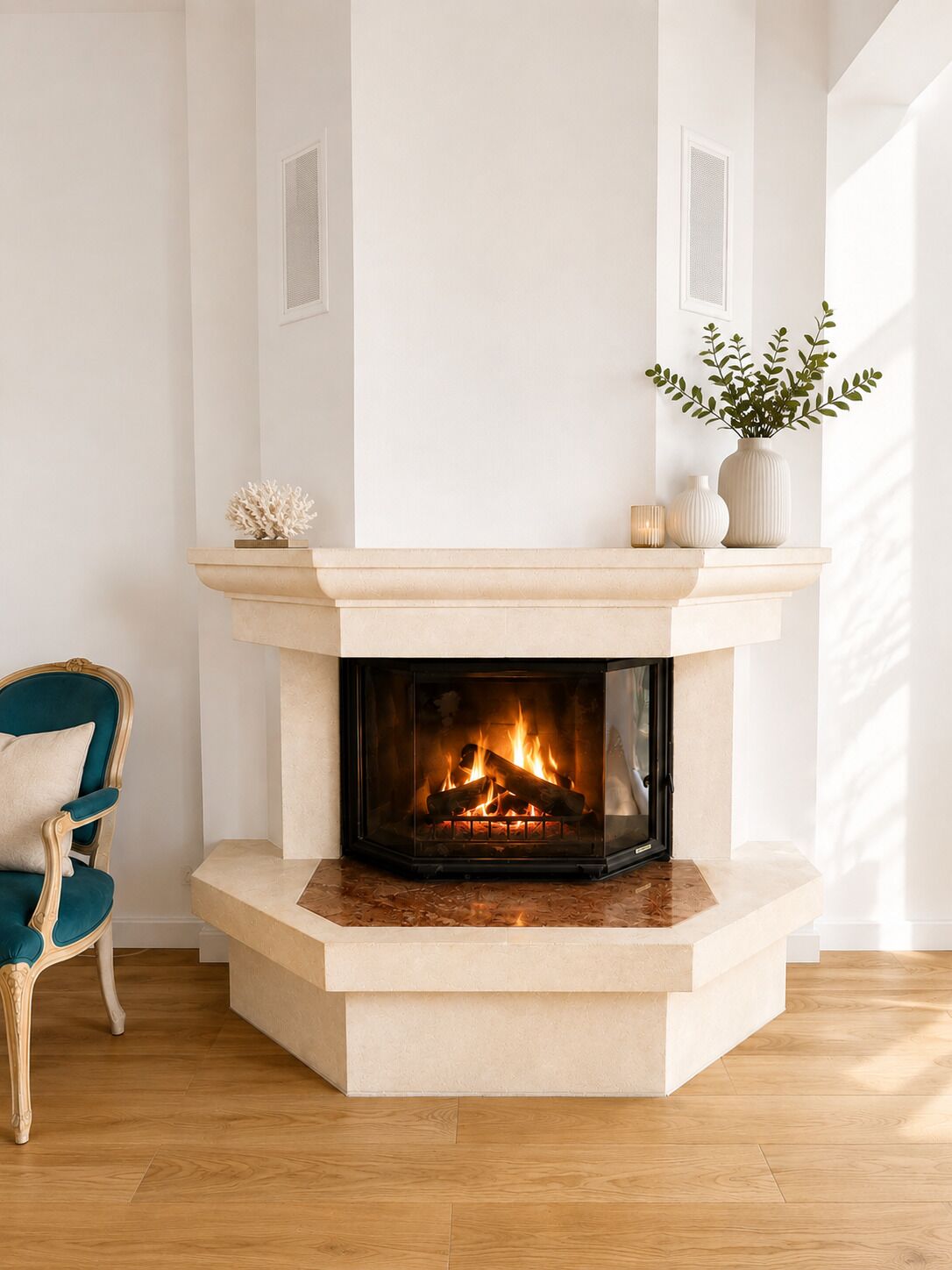 A modern fireplace with a mantel, a teal upholstered chair, and a potted plant.