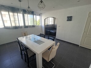 A dining area with a white table, black chairs, and a black sofa. - JULIEN'S 4-ROOM APARTMENT (Tarbes)