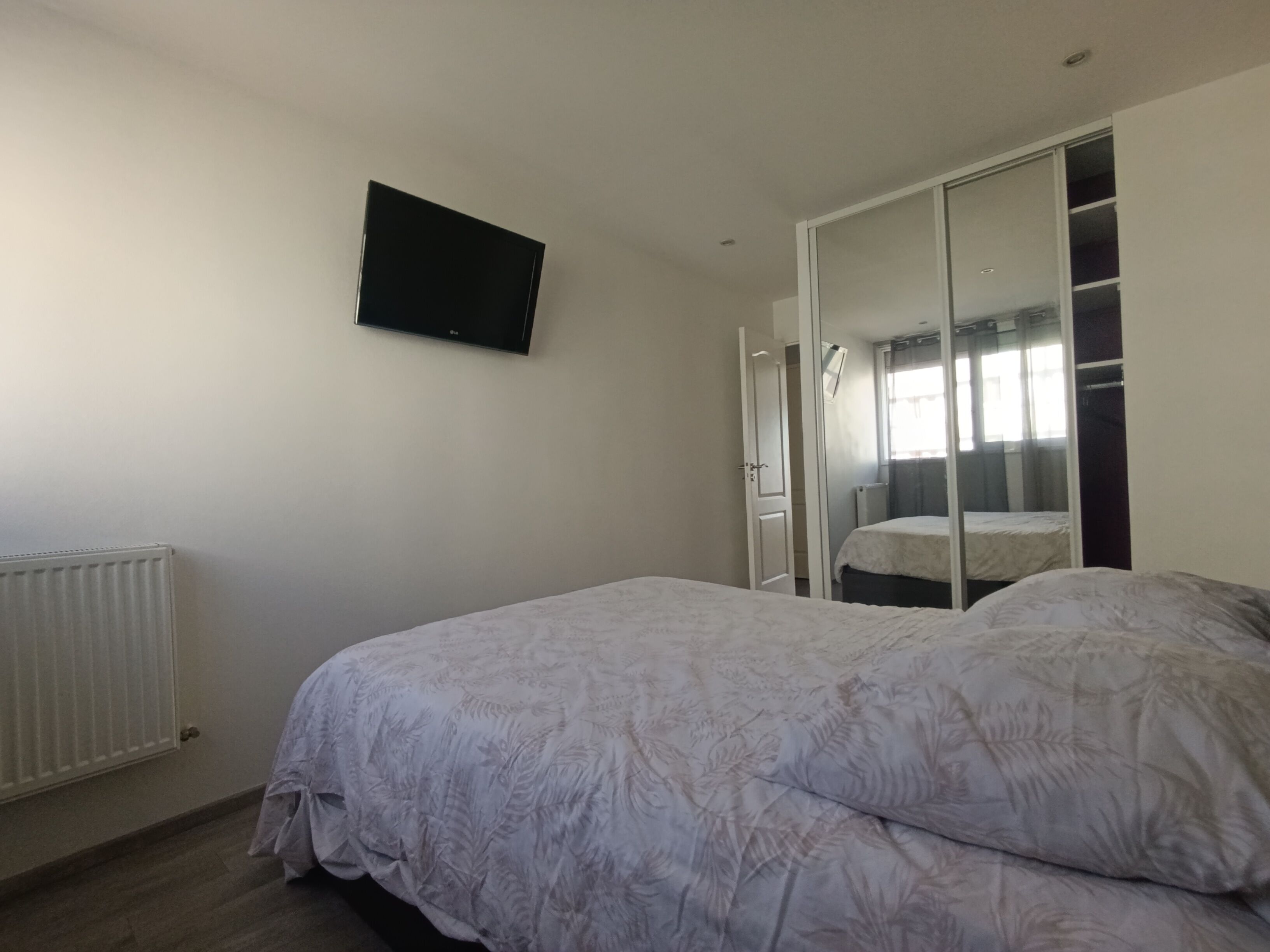 Une chambre à coucher avec un lit, une armoire, un téléviseur et un radiateur.