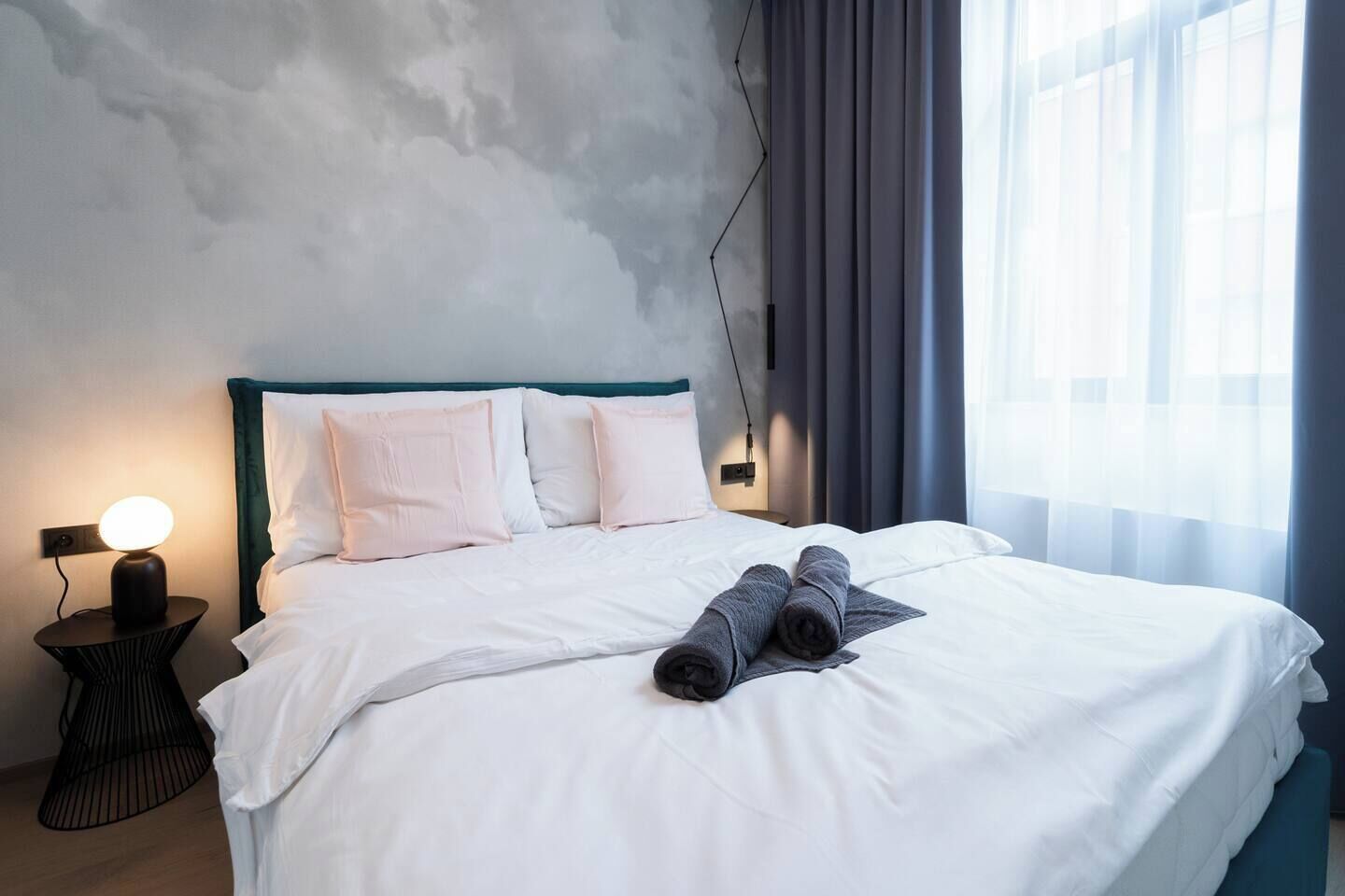Une chambre d’hôtel avec un lit, des oreillers, une lampe de chevet et une fenêtre avec des rideaux.