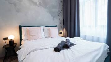 Une chambre d’hôtel avec un lit, des oreillers, une lampe de chevet et une fenêtre avec des rideaux.