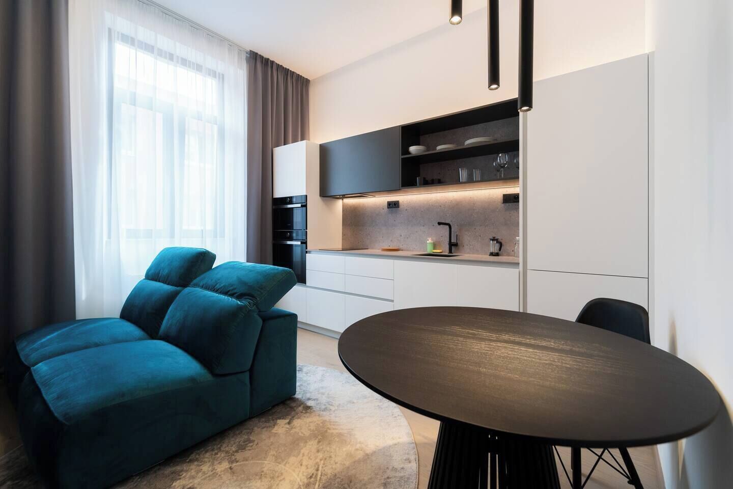 Una sala de estar moderna con un sofá, una mesa de comedor y una cocina amueblada.