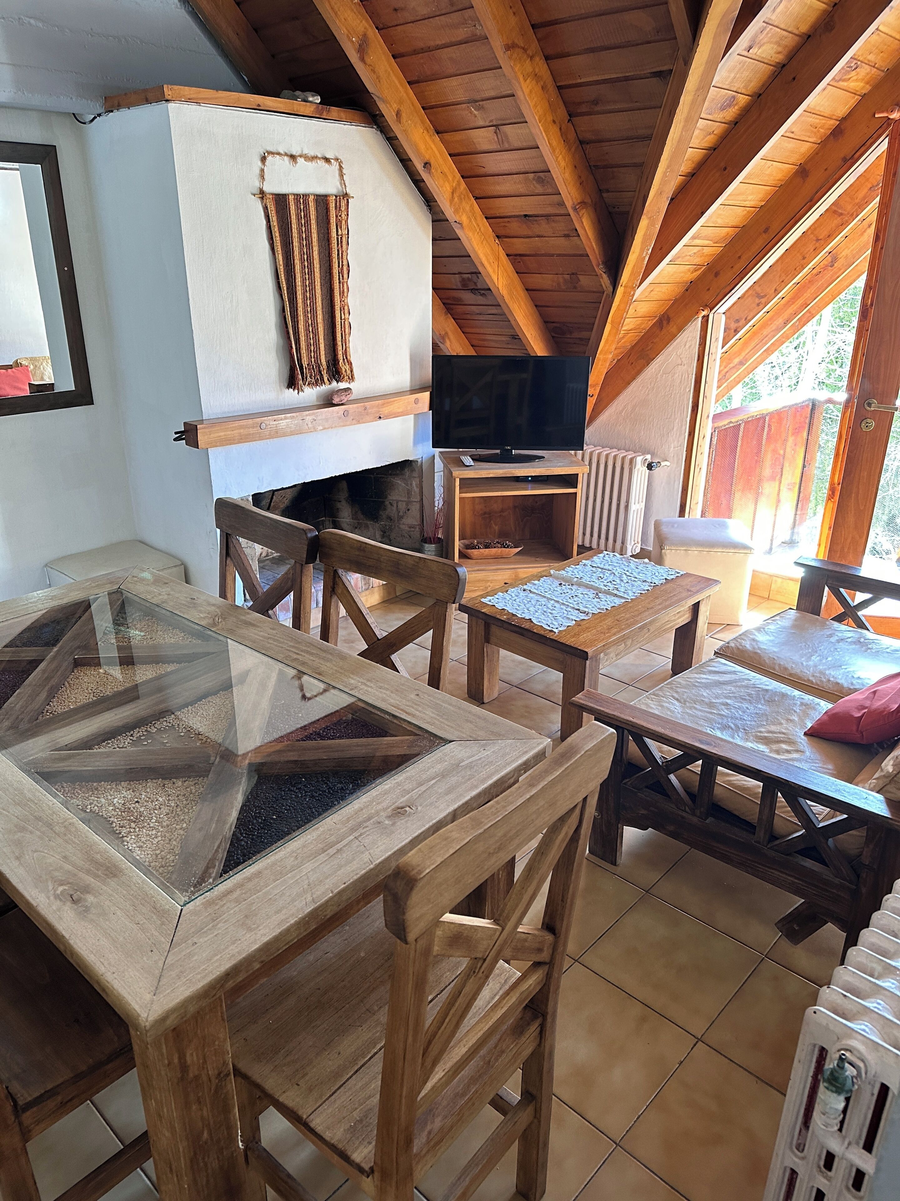 Una habitación acogedora con una mesa de madera, sillas, un televisor y una chimenea.