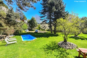 Un giardino sul retro con piscina, una panchina di legno e un tavolo da picnic.