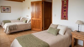 Une chambre avec deux lits, une porte en bois, une lampe et une tapisserie.