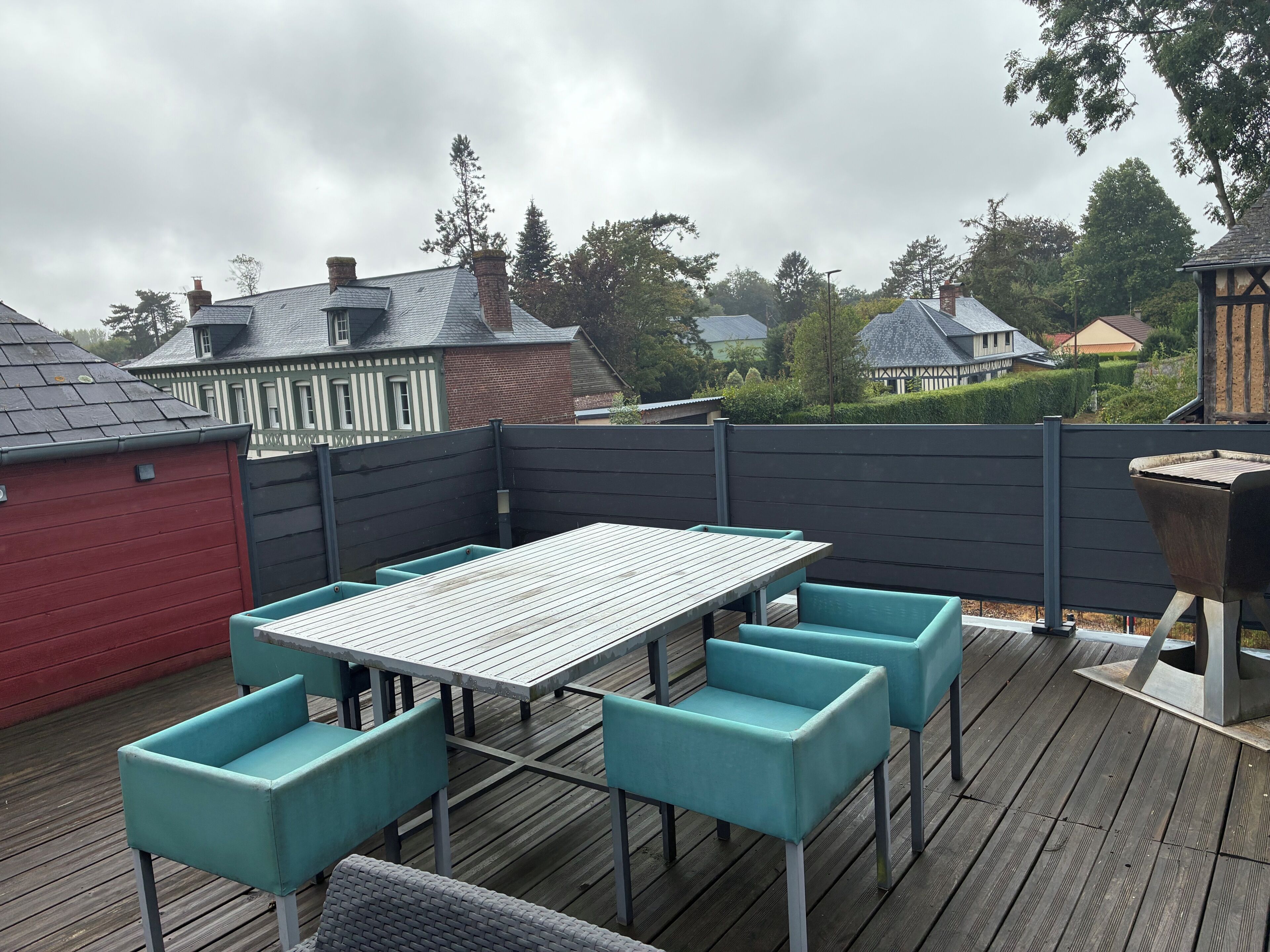 A wooden deck with a table and chairs, surrounded by a fence.