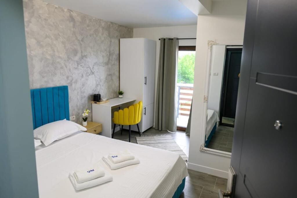 A hotel room with a bed, a desk, a chair, and a view of the outdoors.