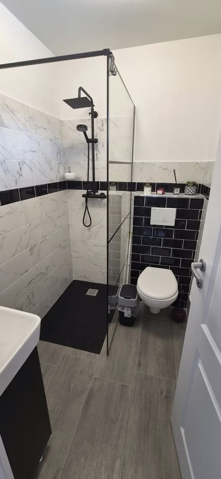 A bathroom with a shower enclosure, a toilet, and a sink.