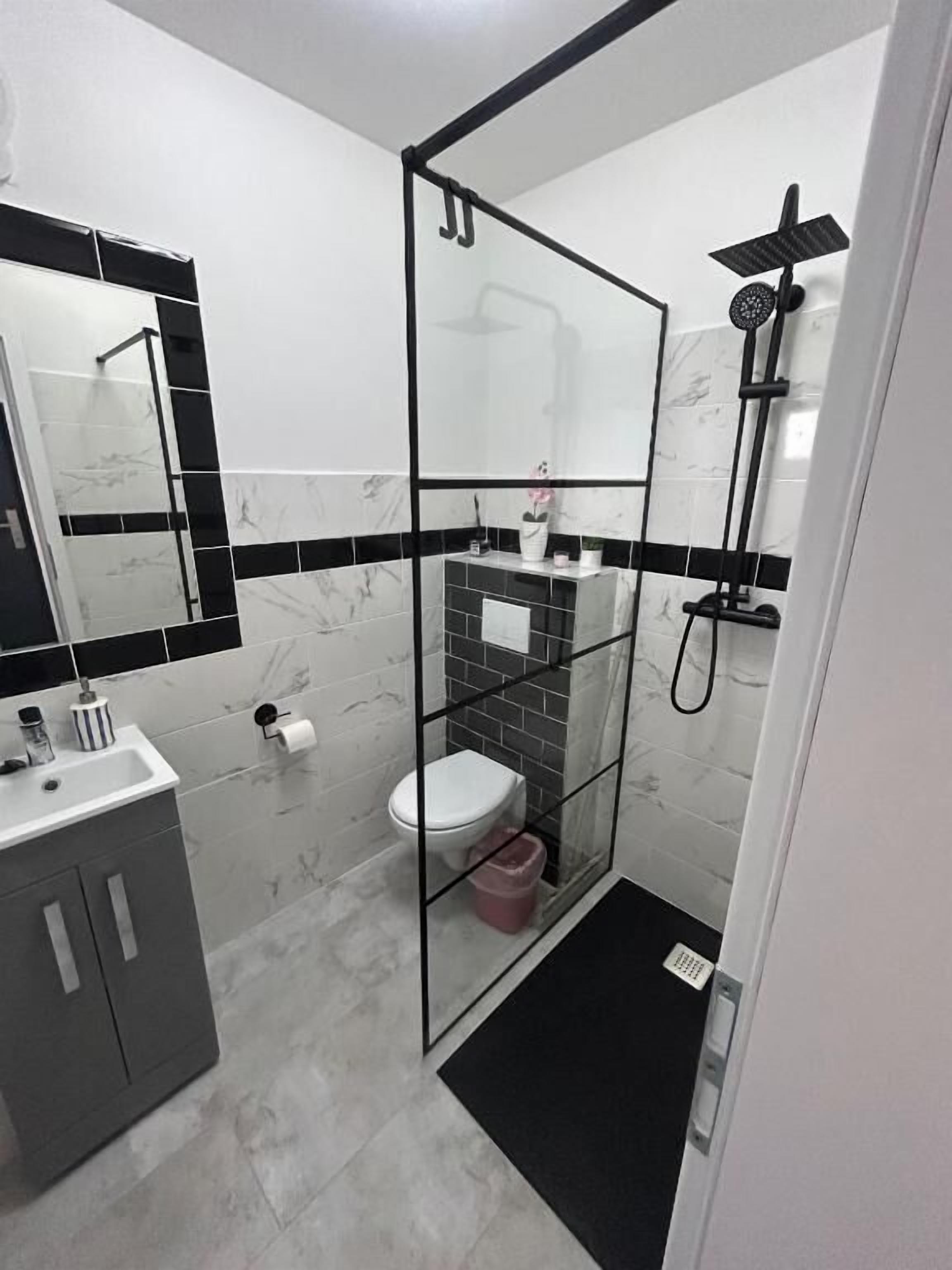 Un baño moderno con ducha envuelta en vidrio, inodoro y lavabo.
