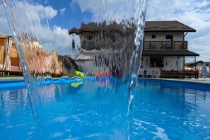 A swimming pool with a clear view of a building in the background. - Good Mood Pool & Smart Rooms (Ciurea)