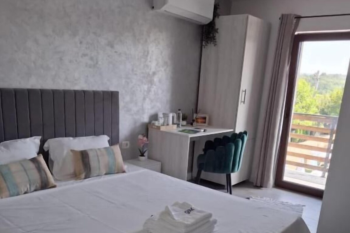 A hotel room with a bed, a desk, and a view of the outdoors.