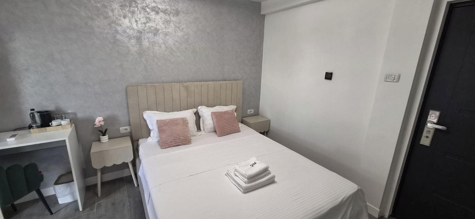 Una habitación de hotel con una cama, mesitas de noche, un escritorio y una silla.