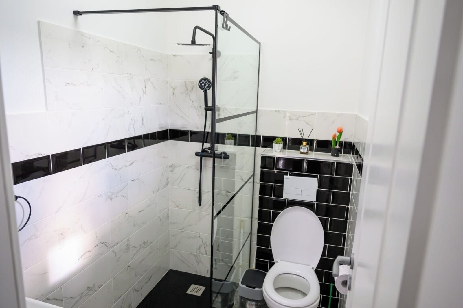 Un baño con cabina de ducha de vidrio, inodoro y lavabo.