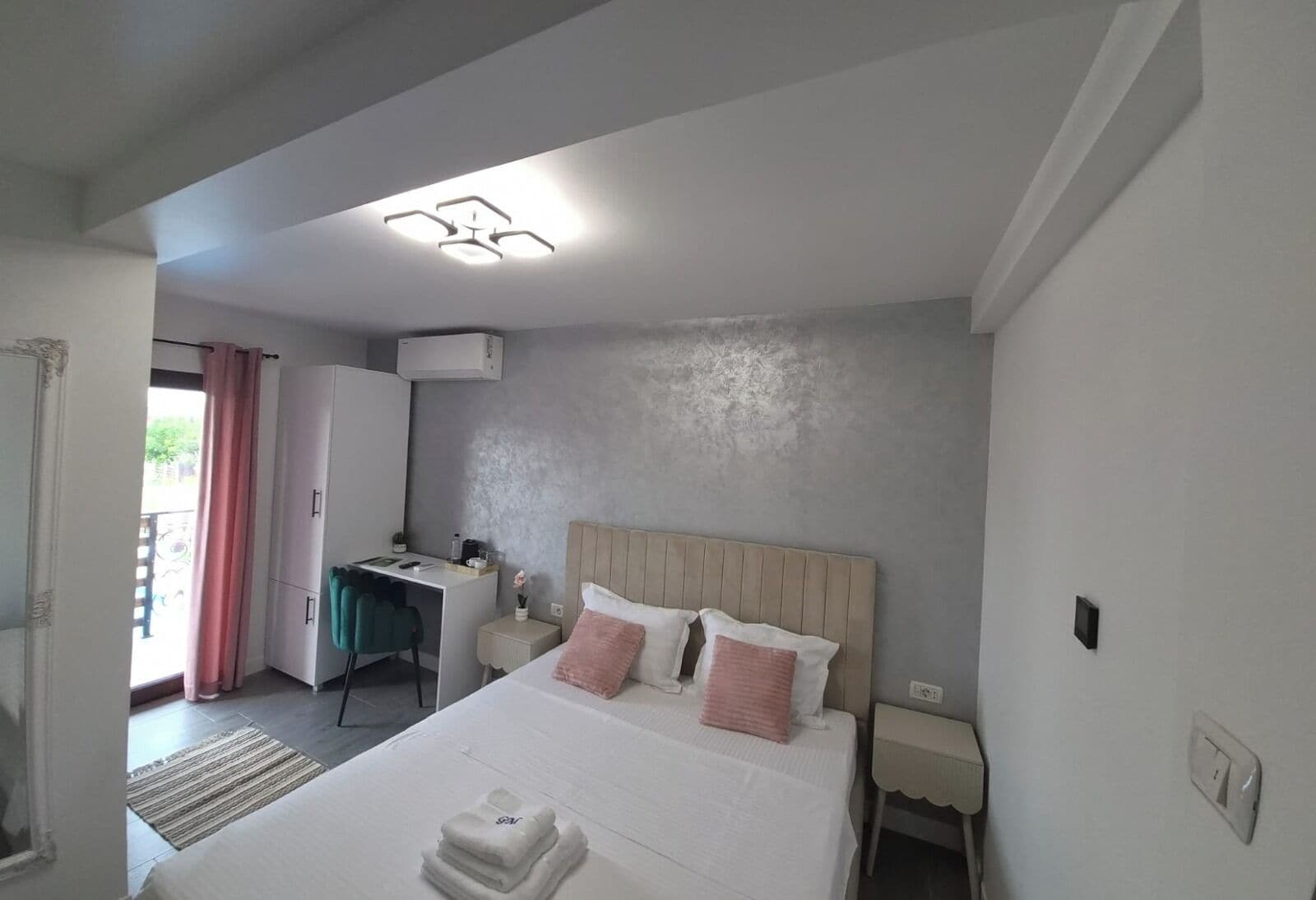 Un dormitorio con cama, mesitas de noche, escritorio y aire acondicionado.