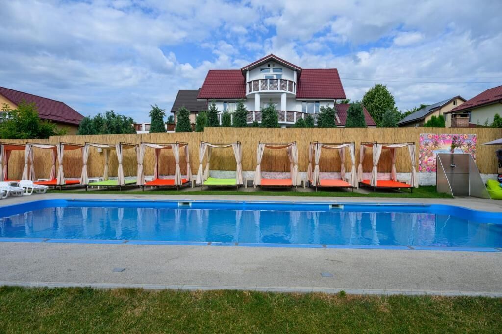 Una piscina con sillas de descanso y un edificio al fondo.