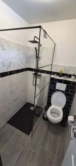 A bathroom with a glass-enclosed shower, a toilet, and a sink.