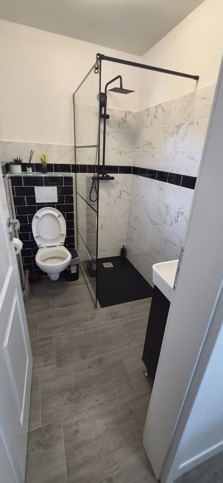 A bathroom with a glass shower enclosure, a toilet, and a sink.