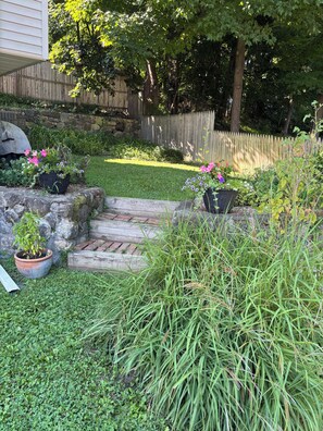 A garden with a stone wall, potted plants, and a wooden fence.
