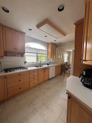 A kitchen with wooden cabinets, a dishwasher, and a coffee maker.