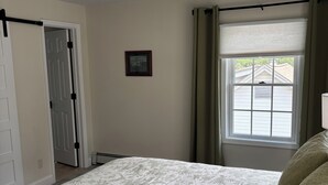A bedroom with a bed, a door, a window with curtains, and a framed picture on the wall. -  Beautiful Light-Filled Home In Charming Historic Cold Spring (Cold Spring)