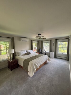 A bedroom with a large bed, two bedside tables, a ceiling fan, and multiple windows.