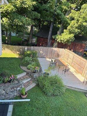 A backyard with a wooden deck, a stone wall, and a fenced area.