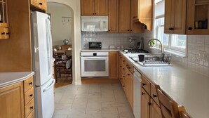 A kitchen with wooden cabinets, a white refrigerator, a microwave, and a stove. -  Beautiful Light-Filled Home In Charming Historic Cold Spring (Cold Spring)