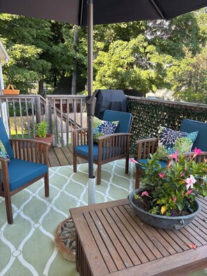 Eine Terrasse im Freien mit Holzmöbeln, einem Tisch mit einem Topfpflanzen und einem überdachten Grillbereich.