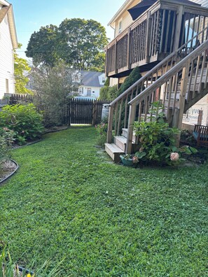 Ein Wohngarten mit einer Holzterrasse, einer Treppe und verschiedenen Pflanzen.