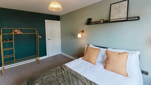 Hotelkamer met een bed, een kledingkast, een plank met decoratieve objecten, een wandklok en een hanglamp.