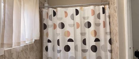 A bathroom with a toilet, a shower curtain with a geometric pattern, and a towel rack.