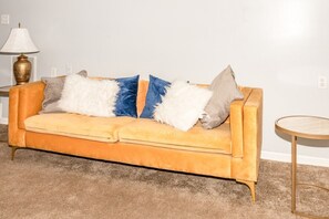 A yellow velvet sofa with multiple cushions in a living room. - Advance Home - McDonough (McDonough)