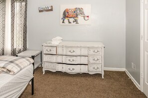 A bedroom with a bed, a dresser, a wall-mounted picture, and a curtain. - Advance Home - McDonough (McDonough)