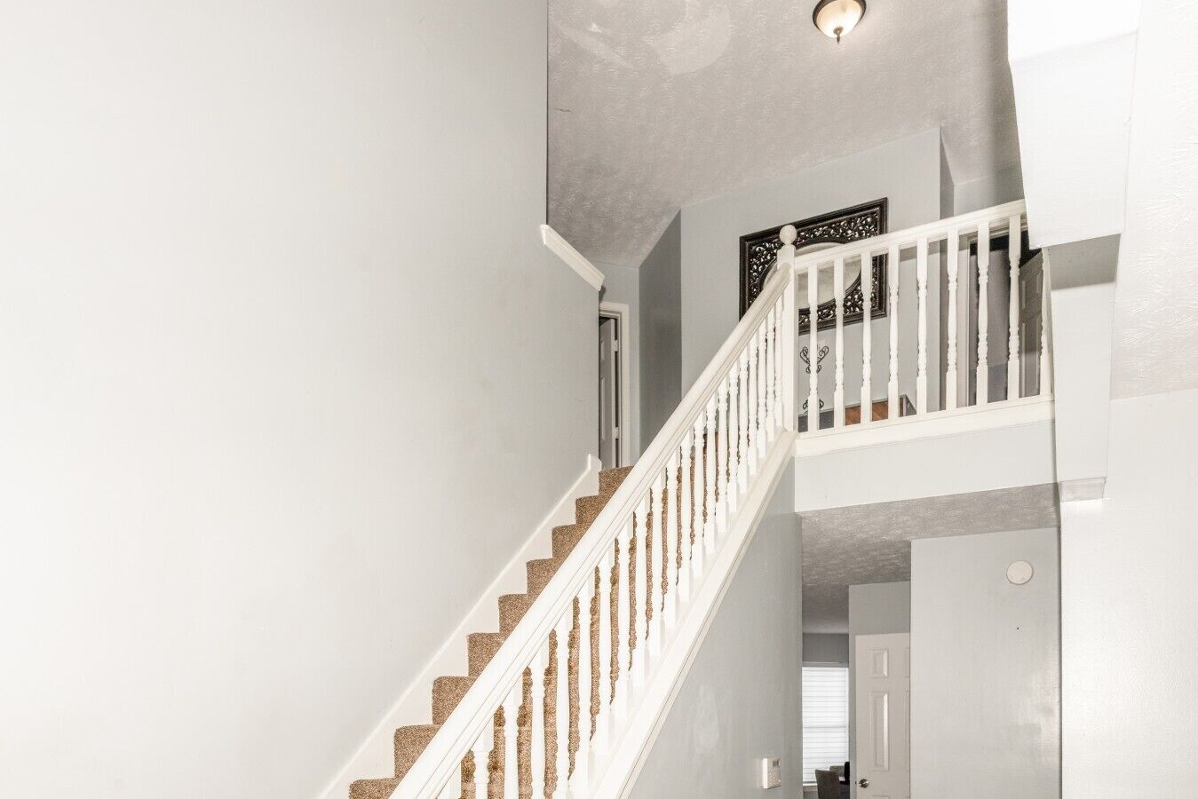 Una escalera con barandillas blancas y un tapete beige que conduce a una plataforma.