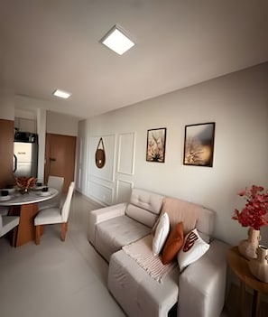 A modern living room with a sofa, a dining table, and chairs. There are framed pictures on the wall. - Apto I Piscina I Wi-Fi I Conforto- Lazer (Cabedelo)