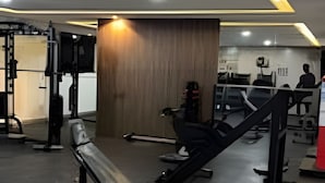 Een sportschool met diverse fitnessapparatuur, zoals een bank en krachttoestellen.