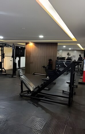 Ein Fitnessraum mit verschiedenen Trainingsgeräten, darunter eine Bank und Gewichtsmaschinen.