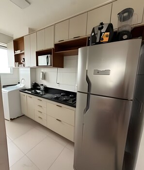 A modern kitchen with a stainless steel refrigerator, a microwave, and a coffee maker on the countertop. - Apto I Piscina I Wi-Fi I Conforto- Lazer (Cabedelo)