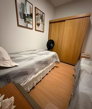 A bedroom with a bed, a wooden wardrobe, and two framed pictures on the wall. - Apto I Piscina I Wi-Fi I Conforto- Lazer (Cabedelo)