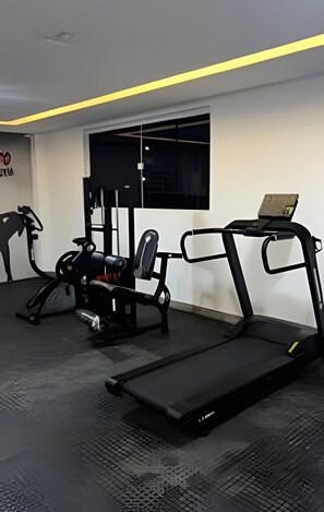 Un gimnasio con cintas de correr, una banca y máquinas de pesas.
