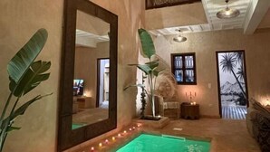 Ein Wellnessbereich mit großem Spiegel, einem grün beleuchteten Pool und einem Balkon mit Aussicht.