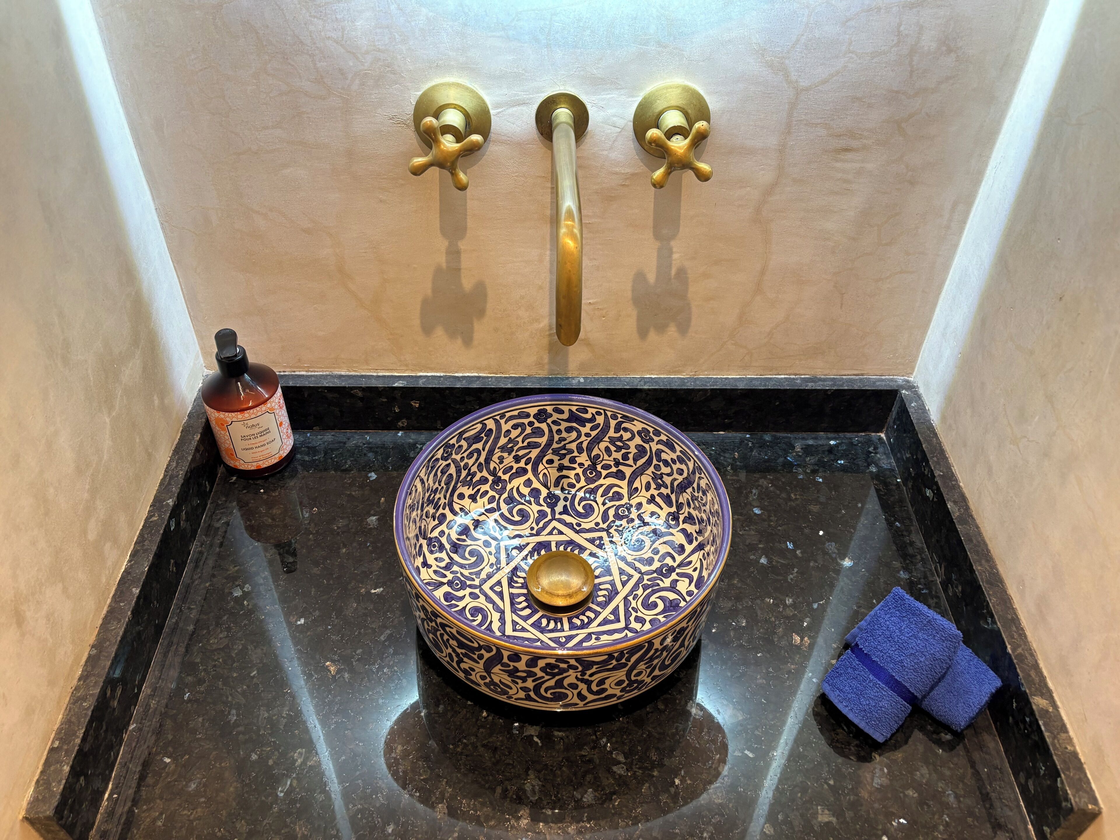 Un baño con un lavamanos, una botella de jabón y un paño azul.