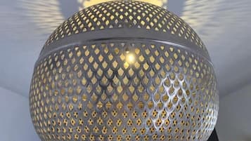Una lámpara araña esférica con diseño decorativo, suspendida del techo, con una luminaria circular al fondo.