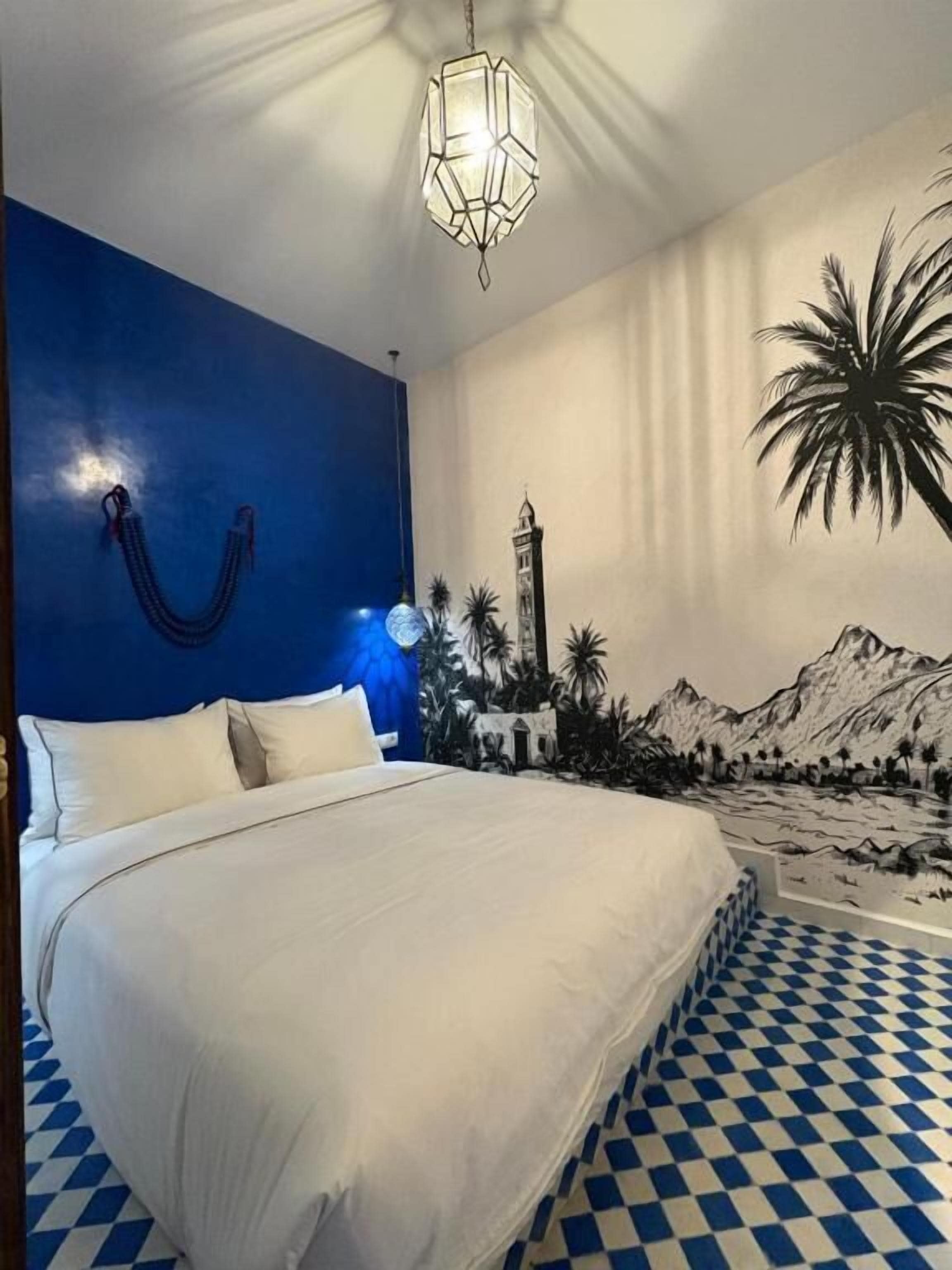 Un dormitorio con cama, pared azul, mural y piso estampado.