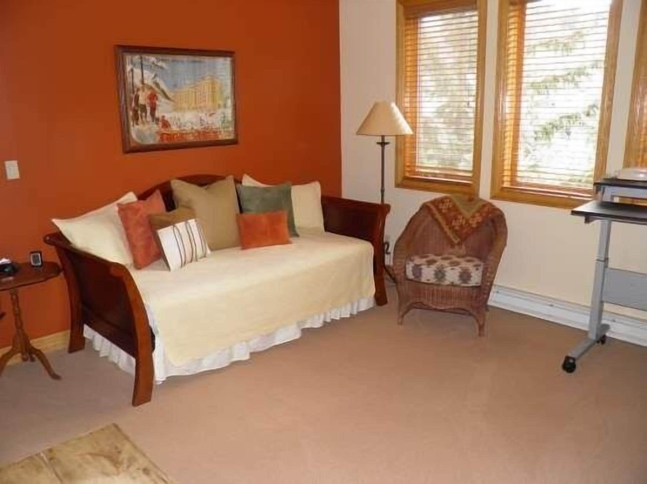 A room with a sofa, a chair, a lamp, and a window with blinds.