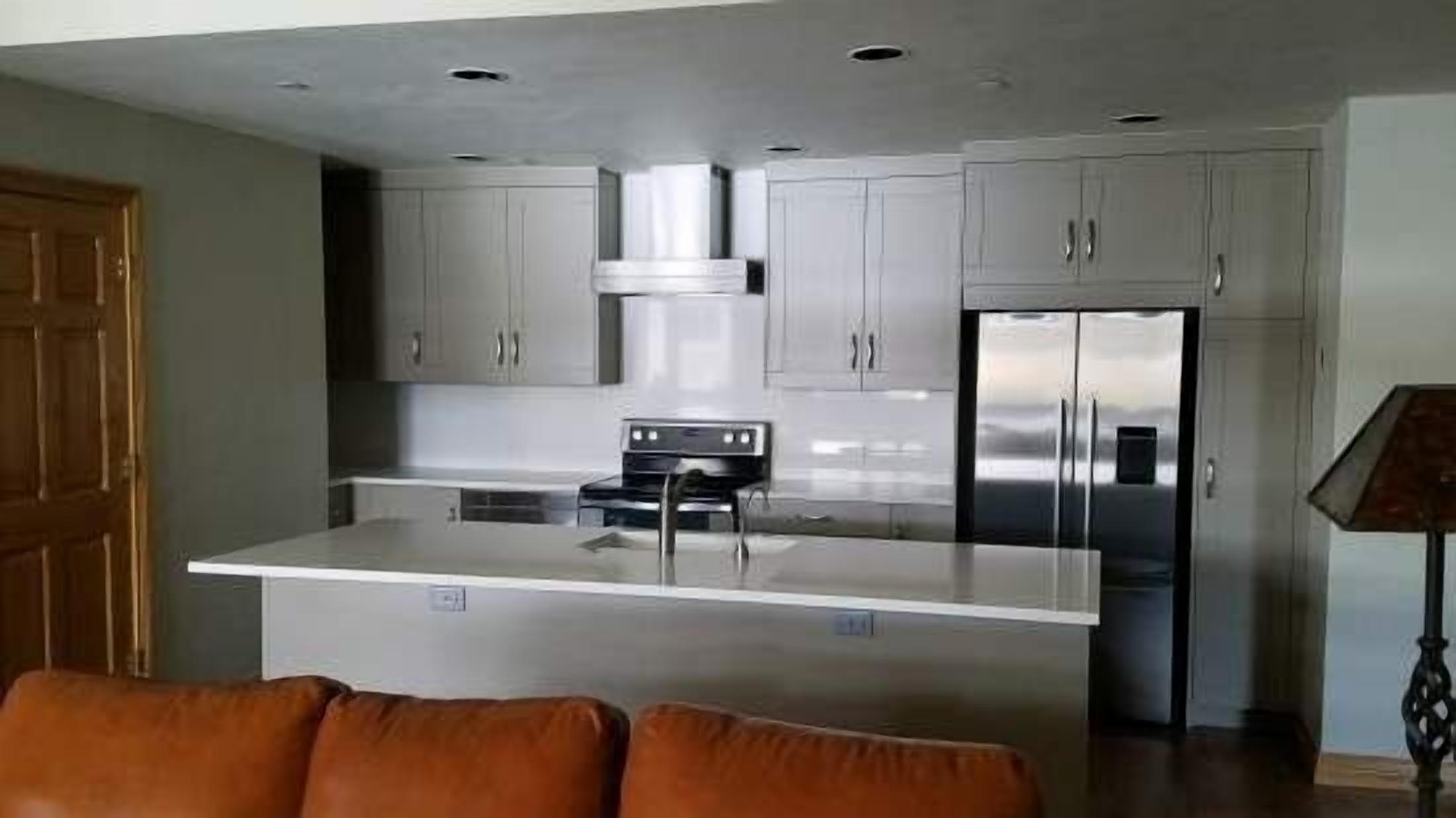 Una cocina moderna con una isla central, electrodomésticos de acero inoxidable y muebles de color claro.