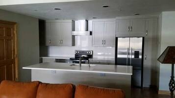 Una cocina moderna con una isla central, electrodomésticos de acero inoxidable y muebles de color claro.