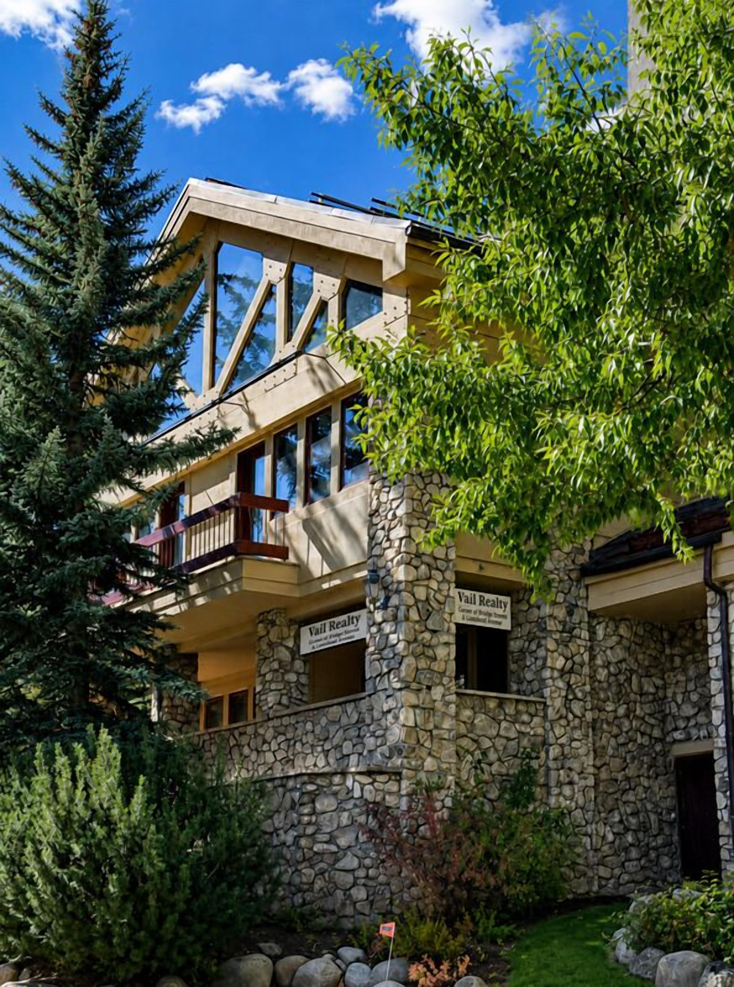 Un edificio de varios pisos con fachada de piedra, balcones y un letrero que dice 'Vail Realty'.