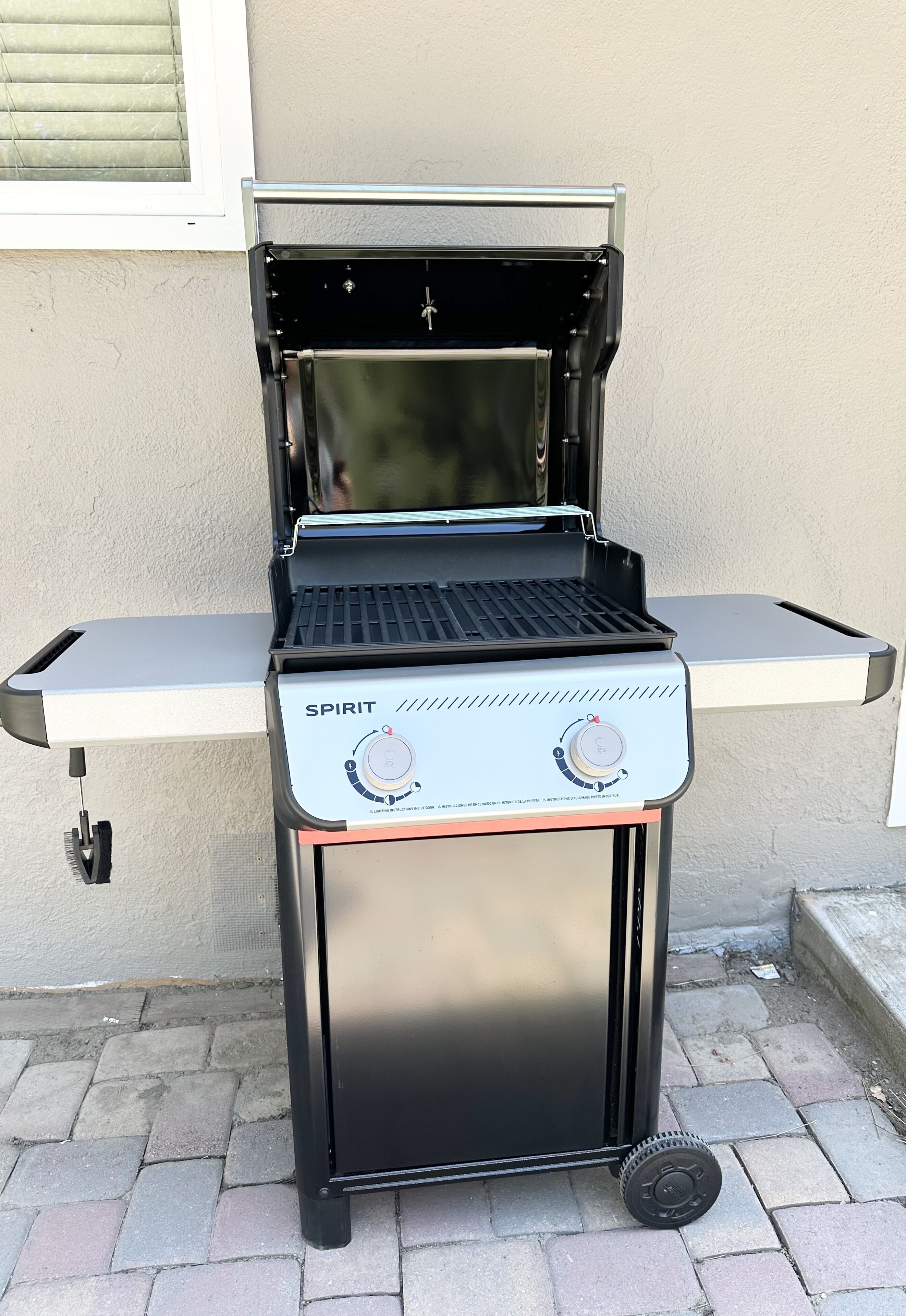 Un barbecue au gaz portatif, doté d’un panneau de commande, d’une table d’appoint et de roulettes.
